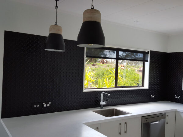 Dark pressed metal splashback behind a kitchen bench and window, from the SPM splashback gallery