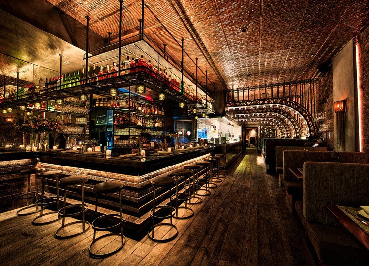 Copper-toned patterned ceiling above a bar with stools and booth seating