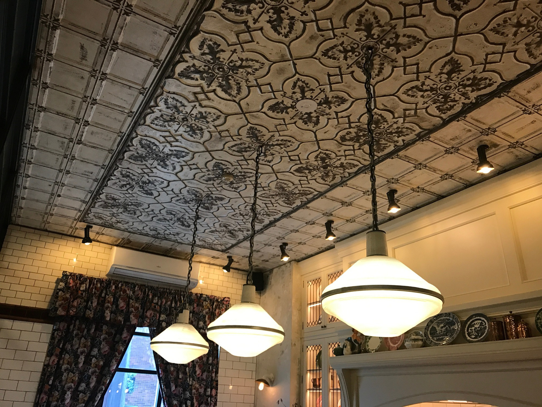 Distressed cream and charcoal patterned ceiling above pendant lights